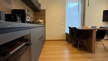 Una cocina moderna con horno integrado y comedor con mesa de madera y sillas negras.