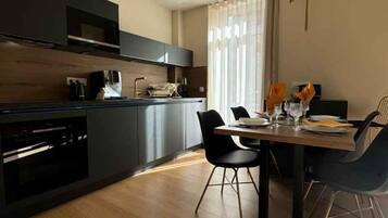A modern kitchen with dark cabinetry, a wooden countertop, and a dining area with a table set for two.