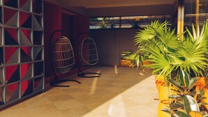 Un interior moderno con piso de baldosas, diseño geométrico en la pared y plantas en macetas.