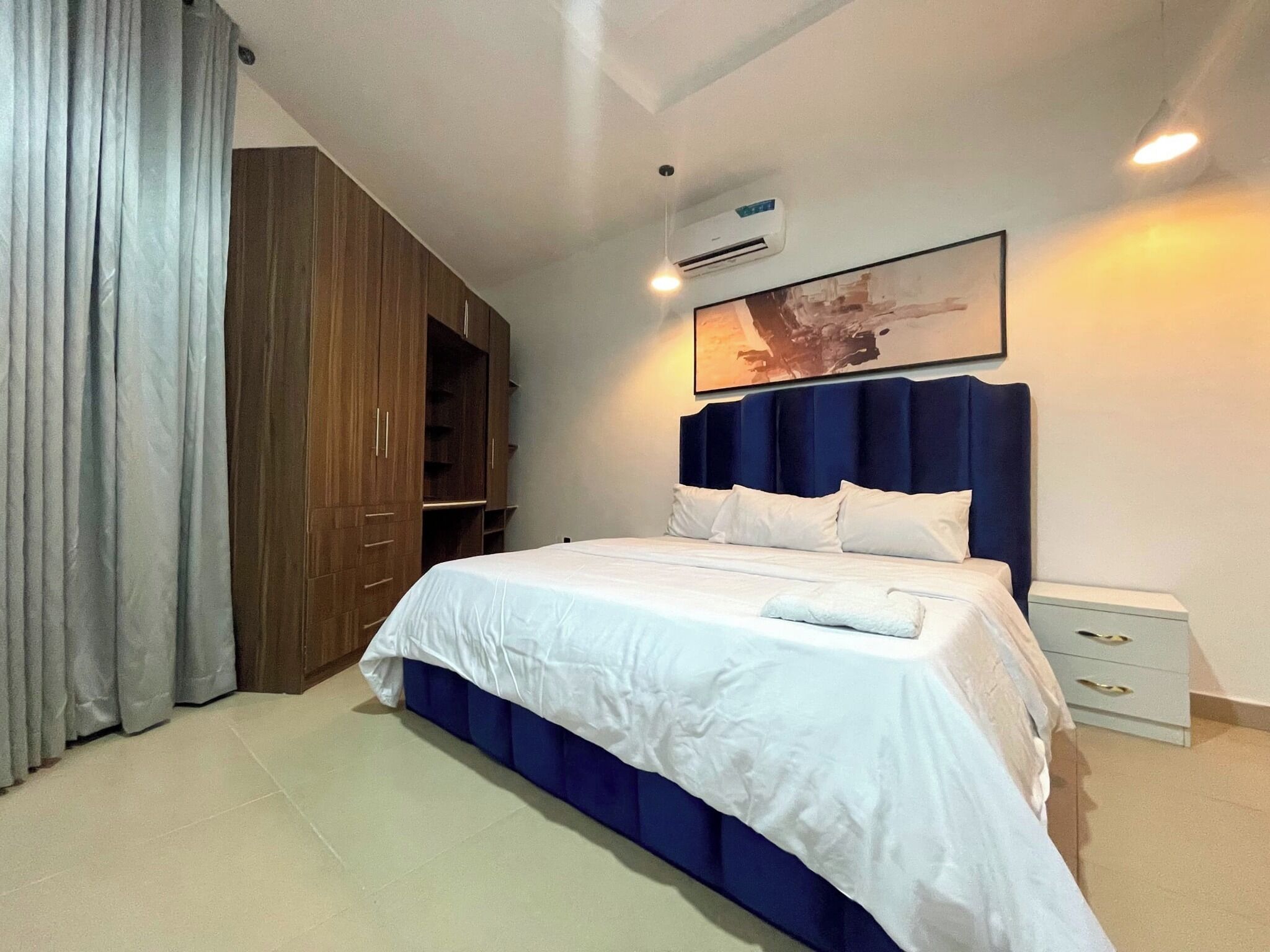 Ein Schlafzimmer mit Bett, Kleiderschrank, Nachttisch und Wandklimaanlage.