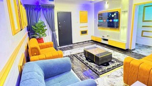A modern living room with a sofa, armchairs, a coffee table, and a TV.