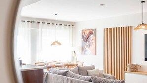 A modern living room with a sofa, a dining area, and a kitchen visible through a round mirror. - Veliero Blu | Kos Marina (Kos)