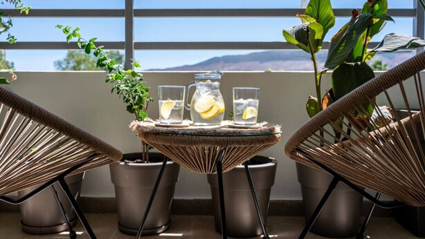 A balcony with wicker chairs, a small table, and potted plants. - Veliero Blu | Kos Marina (Kos)