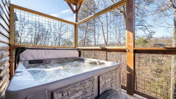 Un jacuzzi en una cabaña de madera con vistas a árboles.