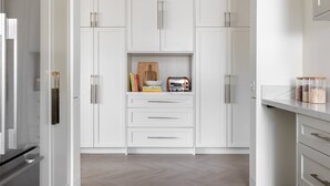 Eine moderne Küche mit weißen Schränken, einem Edelstahlkühlschrank und einer Pendelleuchte.