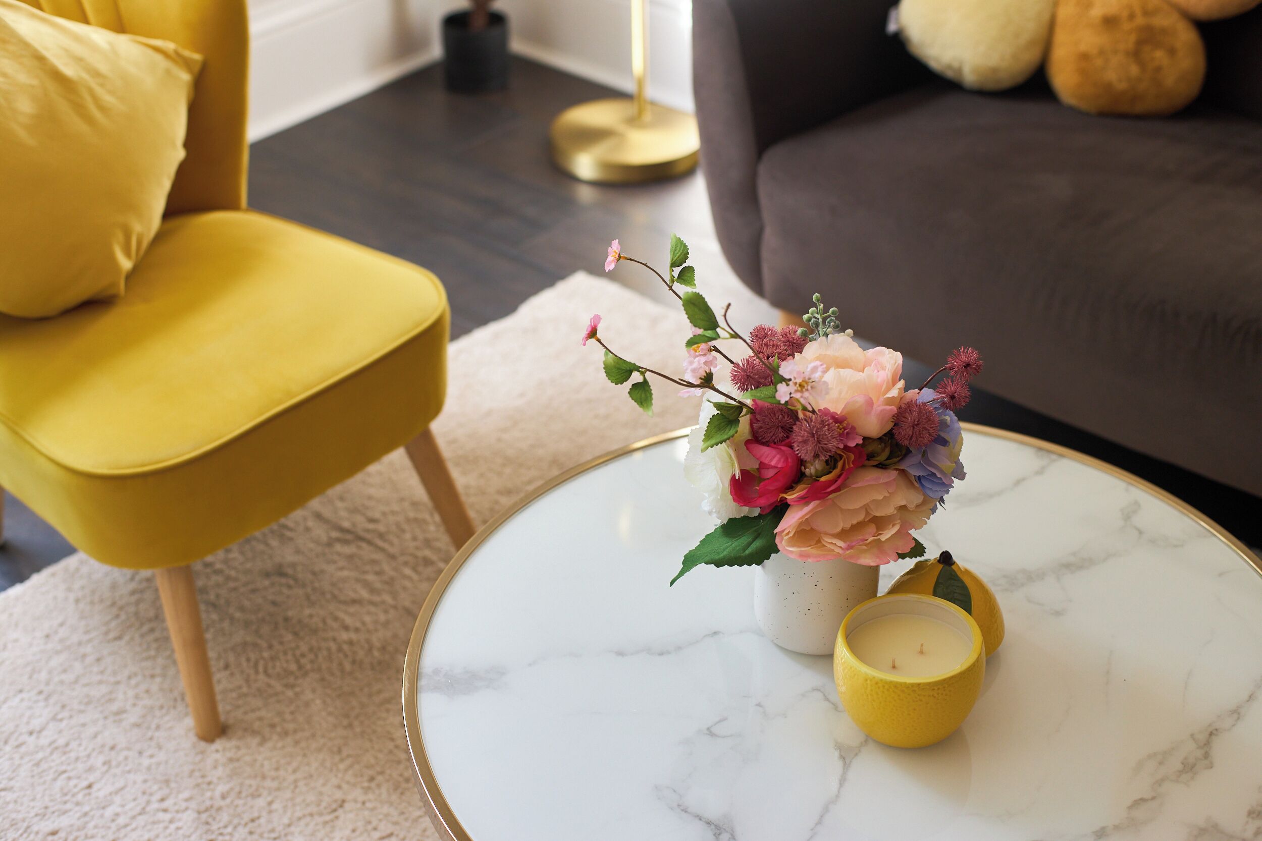 A round marble table with a vase of flowers and candles.