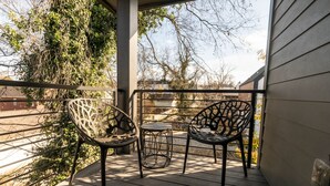 A wooden deck with two metal chairs and a small table, surrounded by a metal railing. - Luxury East Nashville Townhome | Walk to Five Points | Dual King Suites & Arcade Room (Nashville)