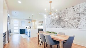 A modern kitchen with white cabinets, a central island, and pendant lighting. - Luxury East Nashville Townhome | Walk to Five Points | Dual King Suites & Arcade Room (Nashville)