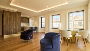Un salon moderne avec un plancher en bois, un fauteuil bleu, un fauteuil blanc et une table à manger en verre avec quatre chaises.