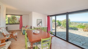 Un espace repas comprenant une table et des chaises, une vue sur l’extérieur et une fenêtre avec des rideaux.