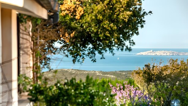 Une vue sur la côte, avec un bâtiment en pierre, une végétation luxuriante et une île au loin.