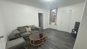Una sala de estar moderna con un sofá gris, una mesa de centro y una televisión.