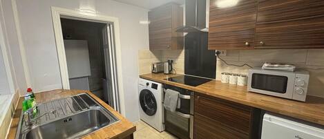 A compact kitchen with a washing machine, a microwave, and a refrigerator.