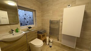 Un baño moderno con lavamanos, inodoro y perchero para toallas.