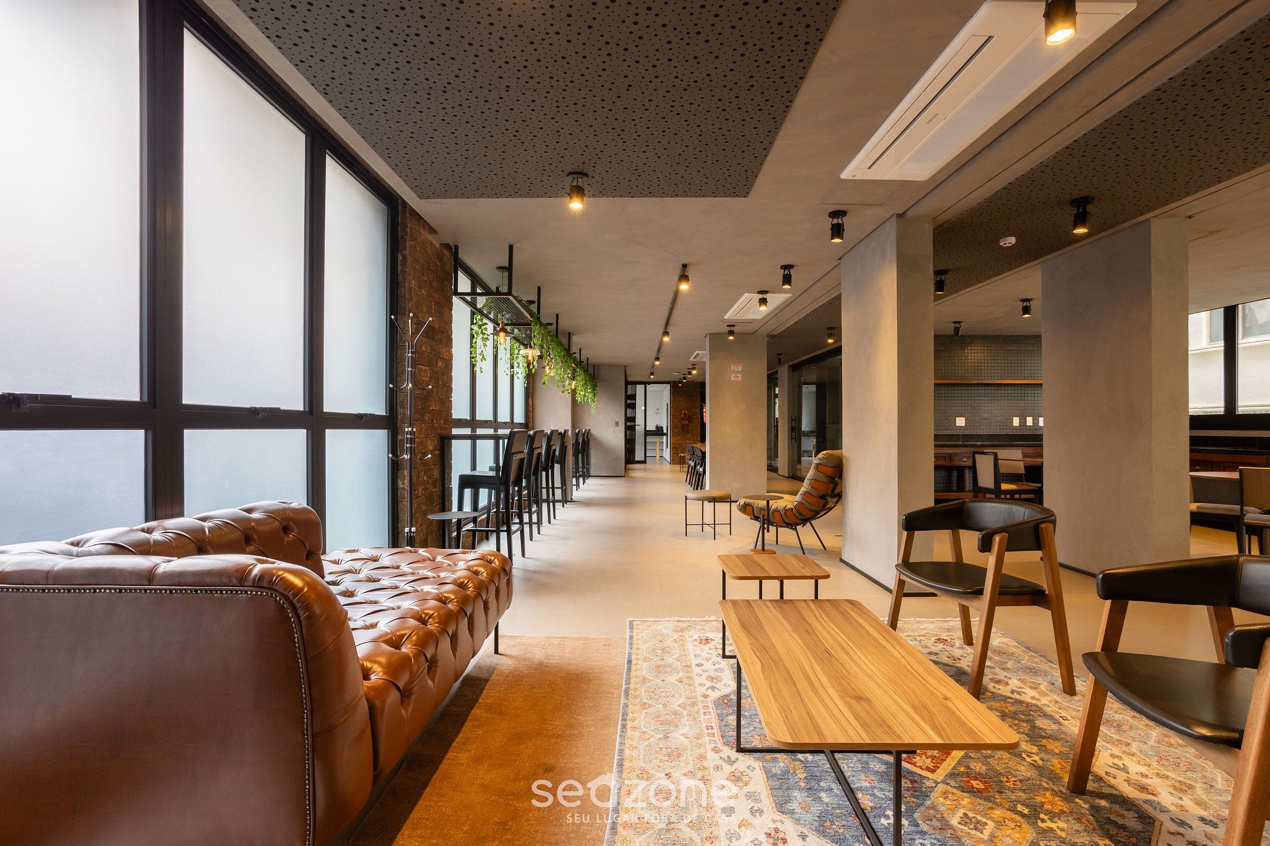 A modern interior with leather seating, wooden tables, and a patterned rug.