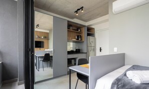 A modern bedroom with a bed, a desk, and a view into a kitchen area. - Comfort and Convenience w/ an Unbeatable Location in Jardim Paulista - Onns (São Paulo)