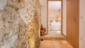 Een stenen muur, een houten deur en een slaapkamer met een bed en nachtkastje.