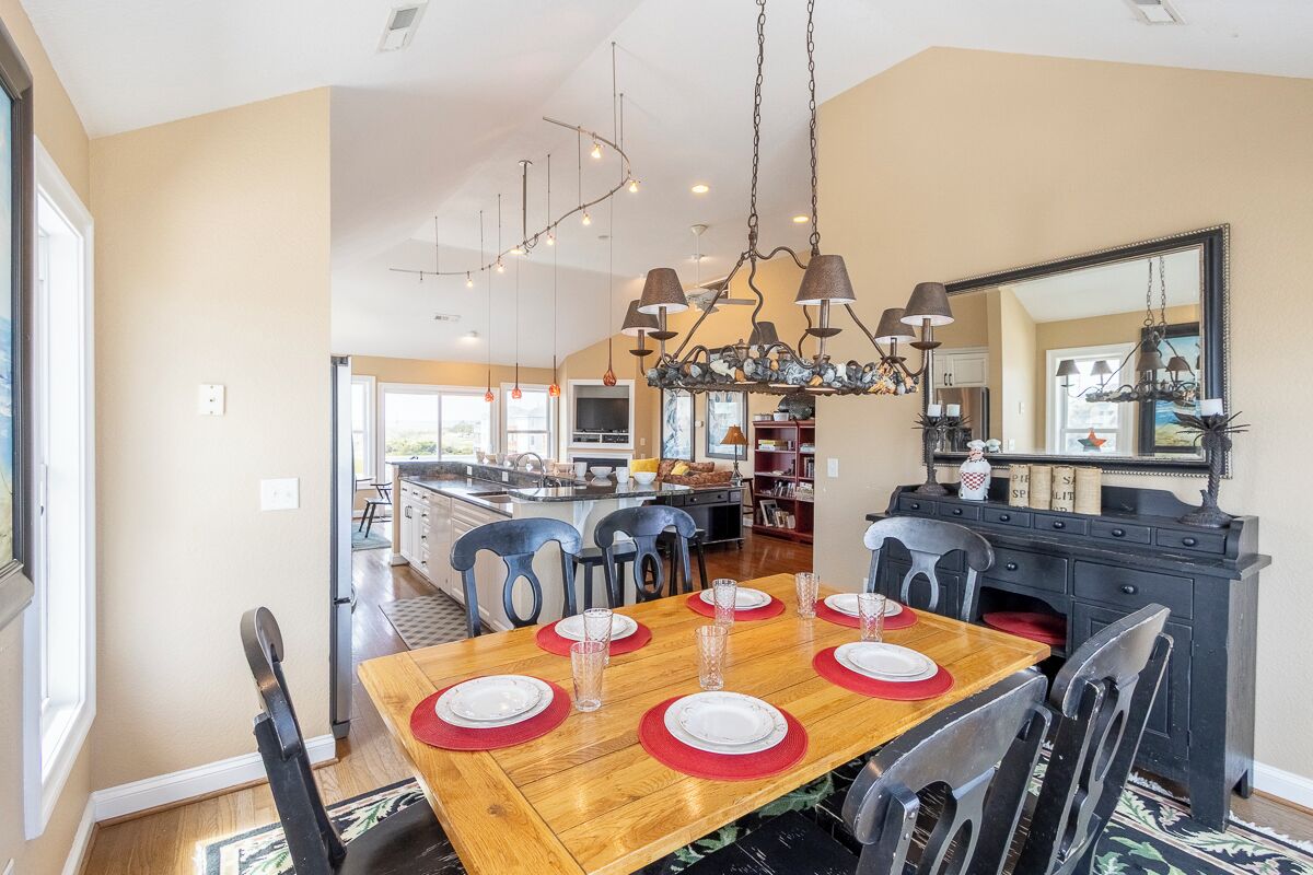 A dining area with a wooden table set for four, surrounded by chairs.