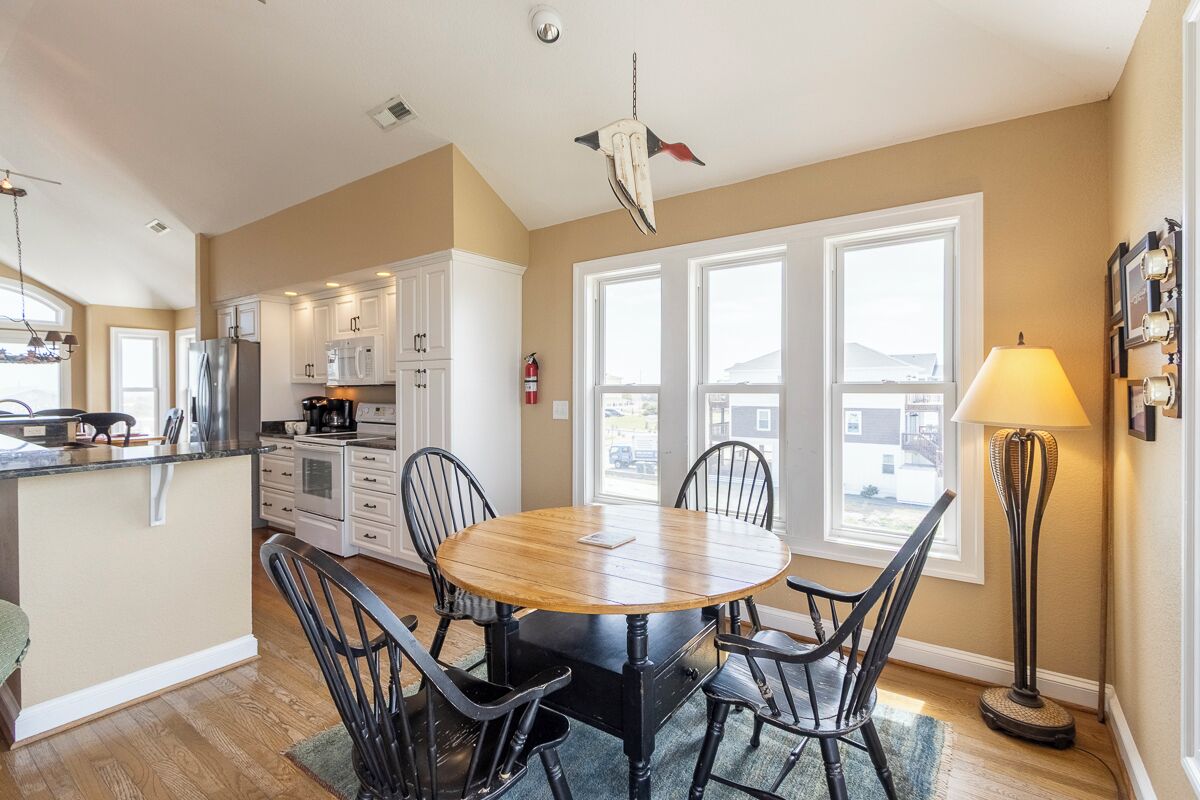 A kitchen with white cabinets, a round wooden table, and black chairs.