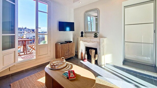 Ein geräumiges Wohnzimmer mit großem Fenster, Kamin, Flachbildfernseher und einer Holzkommode.