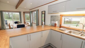 Una cocina moderna con armarios blancos, encimera de madera y un ventanal amplio.