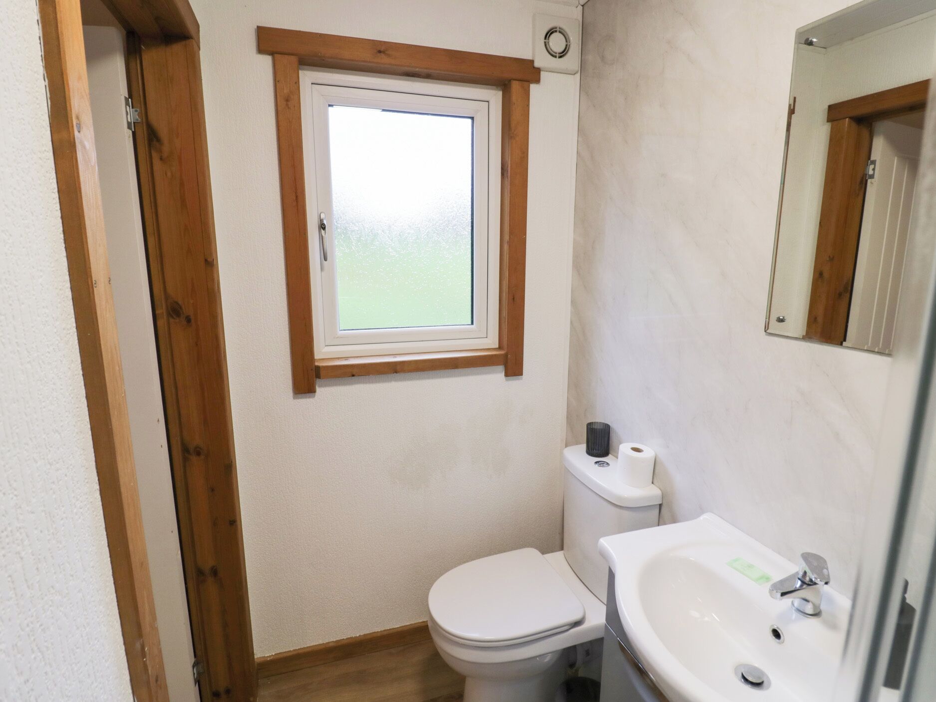 Ein kleines Badezimmer mit Toilette, Waschbecken und Fenster.