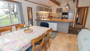 Una cocina acogedora con armarios de madera, una isla central y un comedor con mantel floreado.