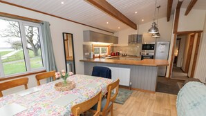 Una cucina accogliente con travi in legno, un tavolo da pranzo con sedie, un frigorifero e vista sull'esterno.