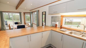 Una cucina moderna con mobili bianchi, un piano di lavoro in legno e un'ampia finestra che offre vista sull'esterno.