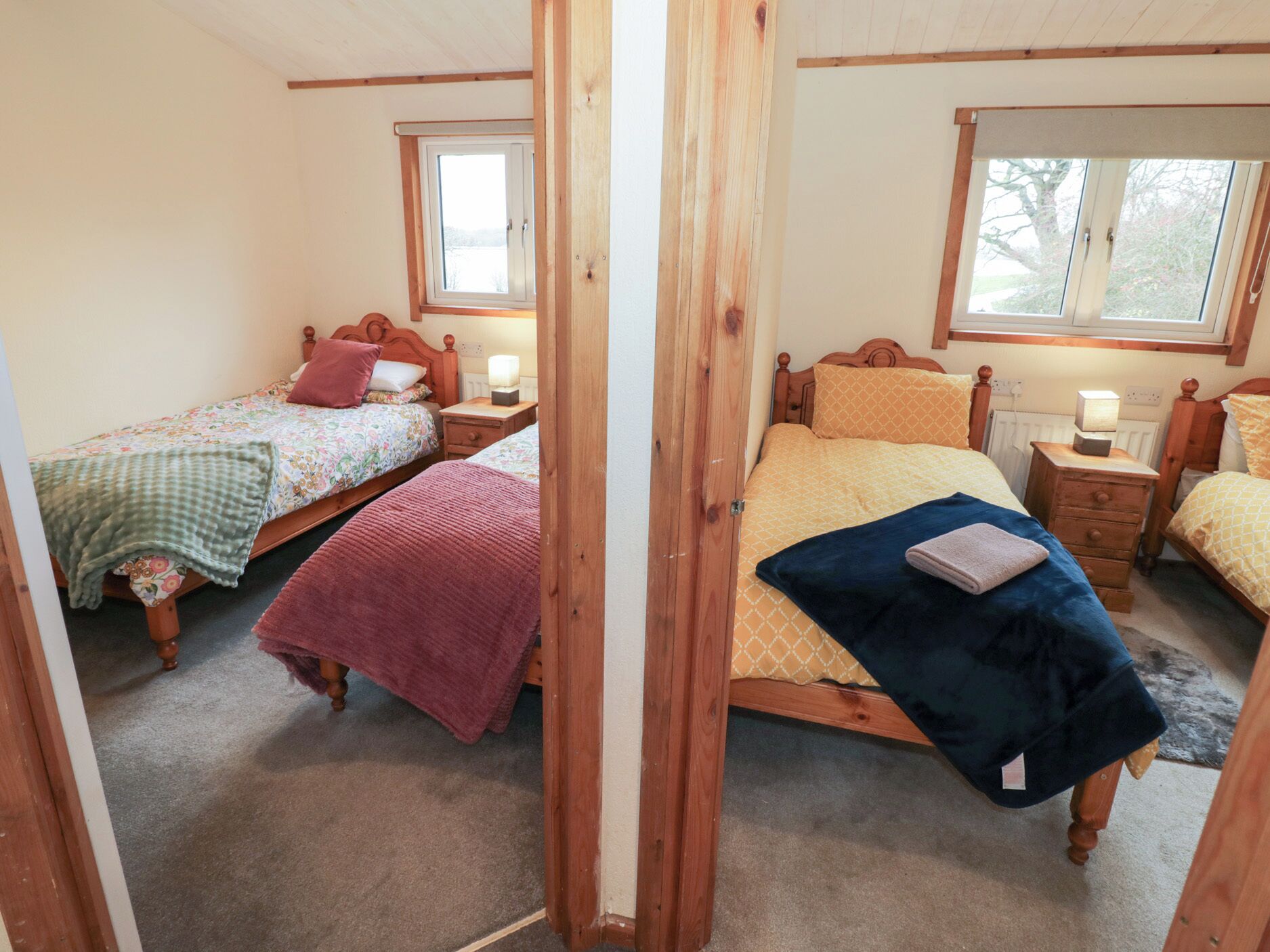 A cozy bedroom with two single beds, each with a bedside table and lamp.