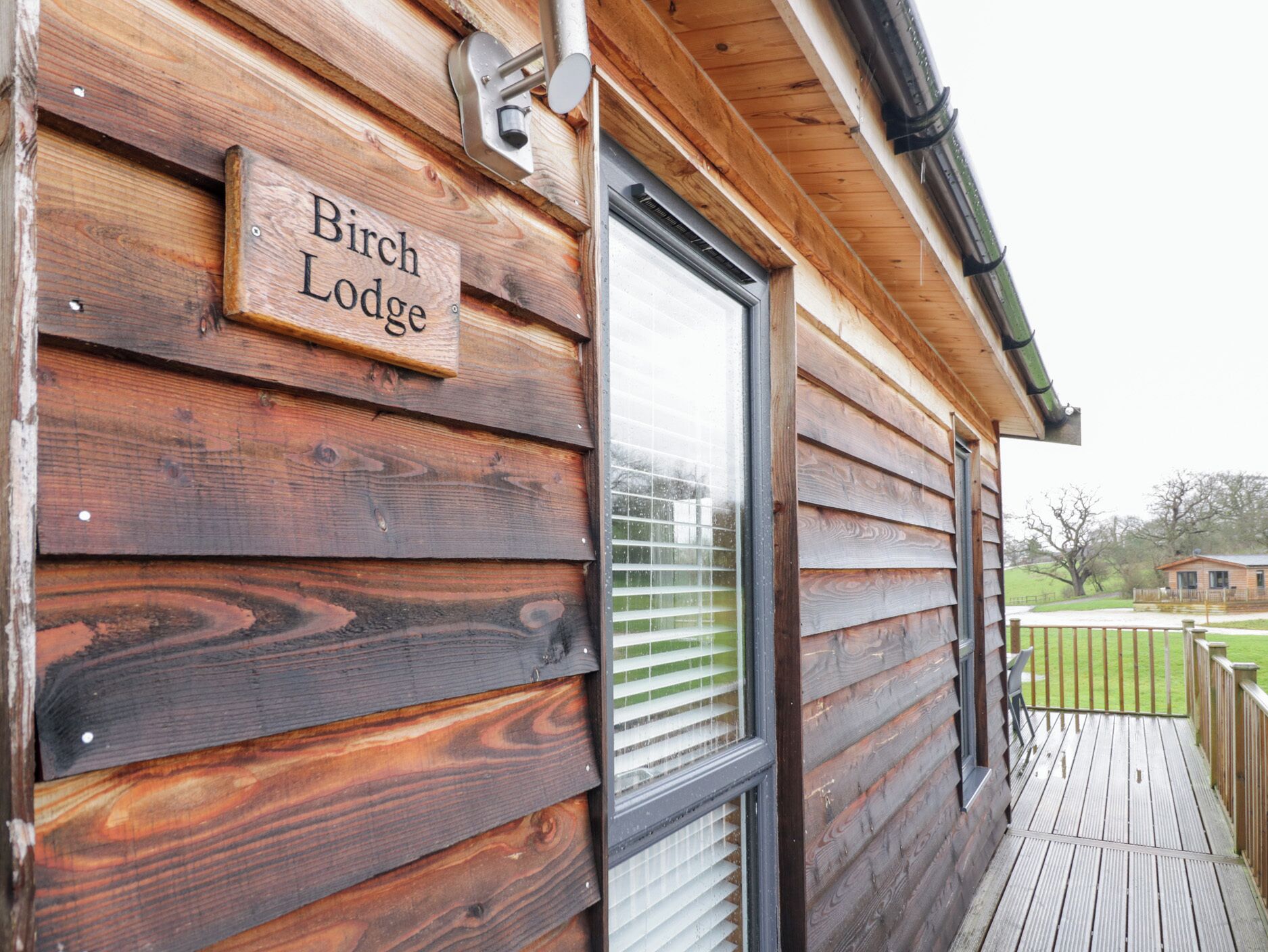 A wooden exterior of a lodge with a sign reading "Birch Lodge".