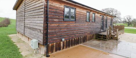 Une cabane en bois avec un porche, une petite terrasse et un porche abrité.