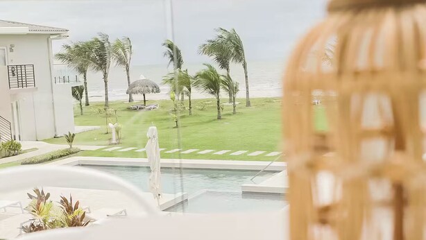 A view from a balcony overlooking a pool, palm trees, and a beach. - Seaview Villa -C2-1D- 2 bed, 2 bath (Punta Chame)