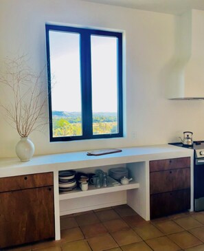 A modern kitchen with a large window, white cabinetry, and a view of the countryside. - Fabulous 4-bedroom estate with guesthouse, pool, and AC in charming Yucca (Yucca)