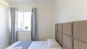 Een hotelkamer met een bed, een raam met gordijnen en een airconditioning.
