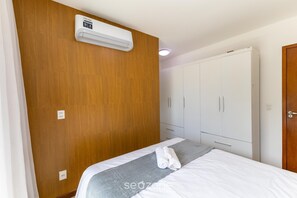 A bedroom with a bed, a grey towel, a white wardrobe, and a ceiling-mounted air conditioner. - 2-suite House 650m From the Beach Juo0004 (Ilhéus)
