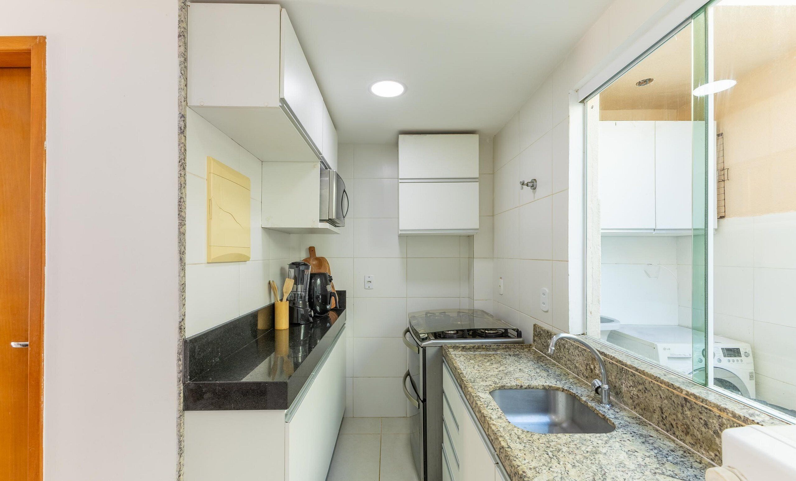 A compact kitchen with white cabinets, a granite countertop, a built-in stove, and a sink.