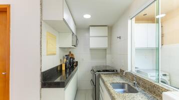 A compact kitchen with white cabinets, a granite countertop, a built-in stove, and a sink.