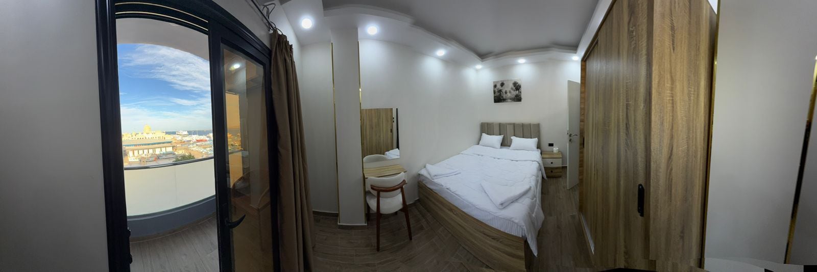 Una habitación de hotel con una cama, mesita de noche y vistas a la ciudad a través de una ventana.