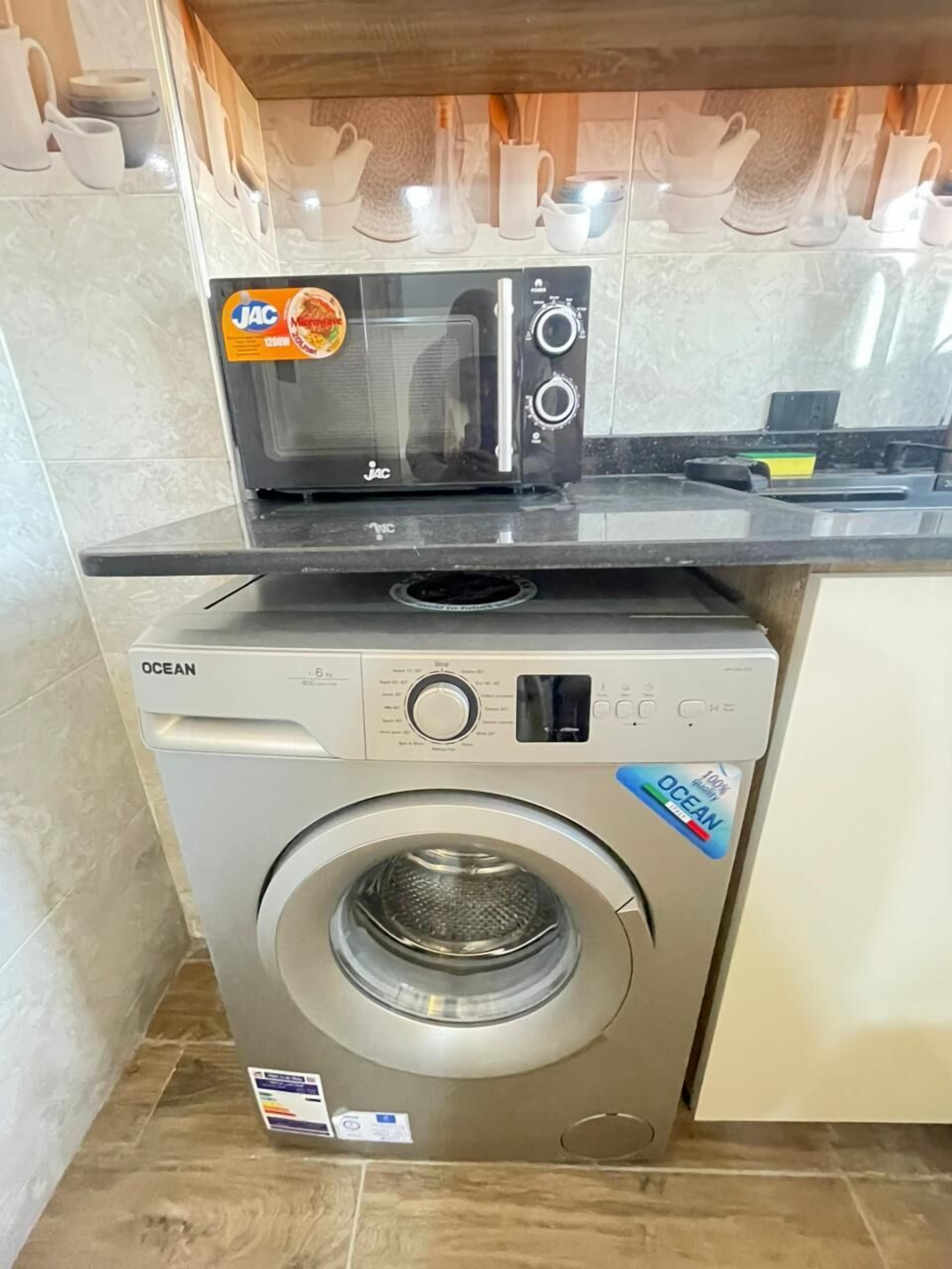 A compact kitchen with a microwave and a front-loading washing machine.