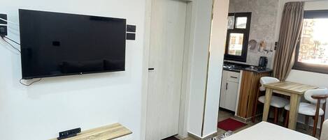 Una sala de estar moderna con un televisor de pantalla plana, un sofá, una mesa de centro de madera y una alfombra estampada.