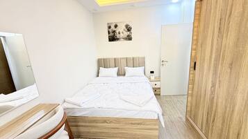 Ein modernes Schlafzimmer mit Bett, Nachttisch, Sessel, Kleiderschrank und einem Bild an der Wand.