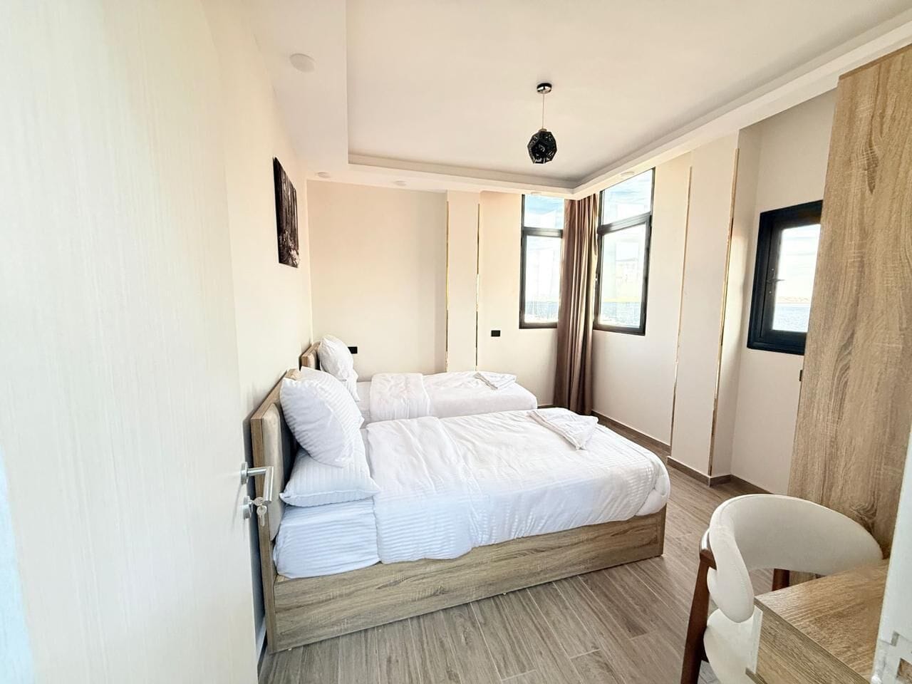A modern bedroom with a wooden bed, a desk, and a chair.