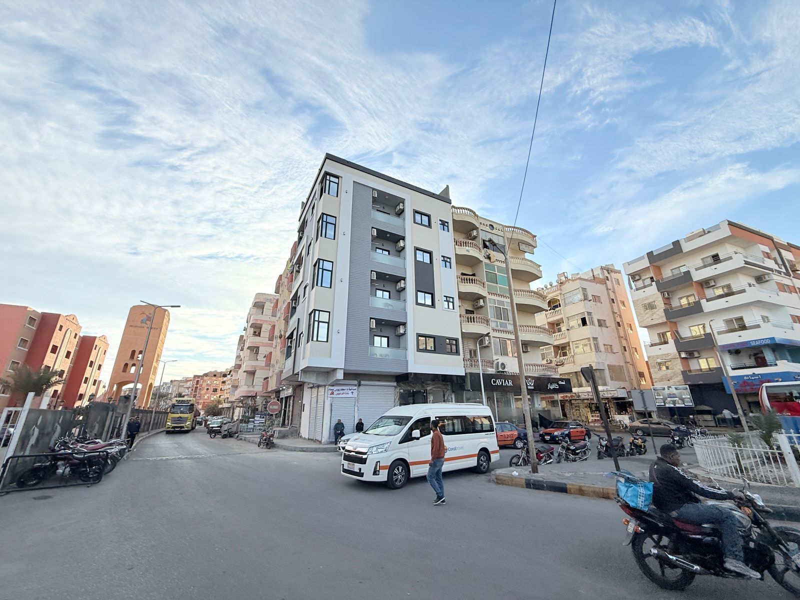 A multi-story residential building with balconies and a street in front.