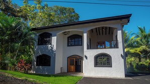 A two-story house with a balcony, a front door, and arched windows. - Casa 78- Bright Modern Pool House with Deck (Esterillos Oeste)