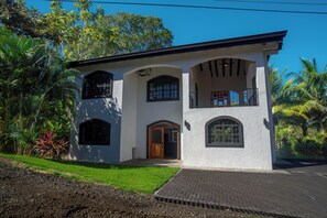 A two-story house with a balcony, a front door, and arched windows. - Casa 78- Bright Modern Pool House with Deck (Esterillos Oeste)