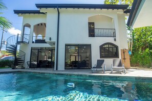 A two-story house with a swimming pool, outdoor seating, and a balcony. - Casa 78- Bright Modern Pool House with Deck (Esterillos Oeste)