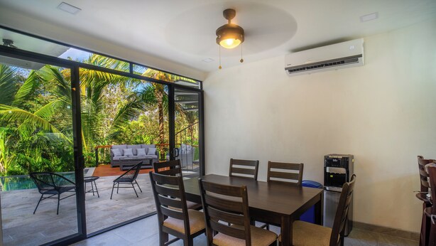 A dining area with a table and chairs, a ceiling fan, and an air conditioning unit. - Casa 78- Bright Modern Pool House with Deck (Esterillos Oeste)