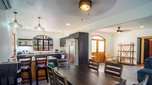 A modern kitchen with dark cabinetry, a central island, and pendant lighting. - Casa 78- Bright Modern Pool House with Deck (Esterillos Oeste)