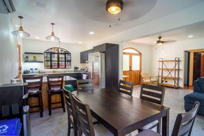 A modern kitchen with dark cabinetry, a central island, and pendant lighting. - Casa 78- Bright Modern Pool House with Deck (Esterillos Oeste)